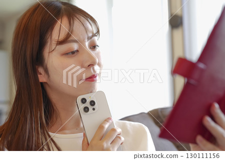 一位女士坐在沙發上查看她的日程安排 一位女士坐在沙發上查看她的日程安排 130111156