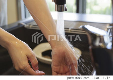 Woman washing her hands in the kitchen (no face) 130111216