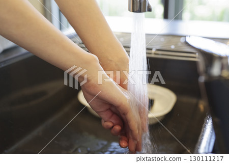 Woman washing her hands in the kitchen (no face) Woman washing her hands in the kitchen (no face) 130111217