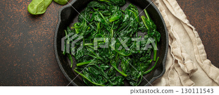 Healthy steamed spinach in cast iron pan on brown rustic background top view Healthy steamed spinach in cast iron pan on brown rustic background top view 130111543