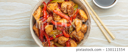 Asian stir fry chicken with red and green peppers and sesame seeds in bowl with chopsticks and soy sauce top view on white wooden table Asian stir fry chicken with red and green peppers and sesame seeds in bowl with chopsticks and soy sauce top view on white wooden table 130111554