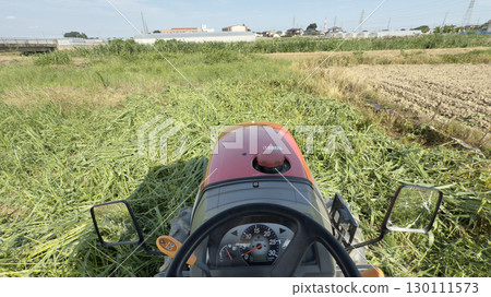 Shooting from the driver's seat of a tractor, plowing a field of grass 130111573
