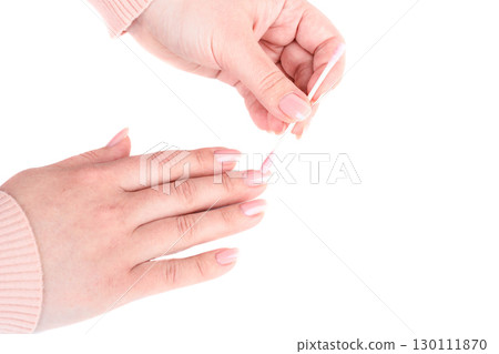 Female hands cleaning nails with manicure using pink cotton swab. 130111870