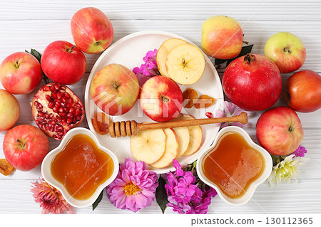 Jewish holiday Rosh Hashanah concept with apples, honey, pomegranate and flowers for greeting card, creative layout and template for Jewish New Year and Thanksgiving, autumn banner for design. 130112365