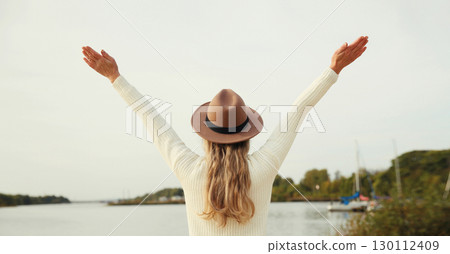 Happy stylish woman traveler on beach, enjoying warm weather, wear hat standing on sea coast Happy stylish woman traveler on beach, enjoying warm weather, wear hat standing on sea coast 130112409