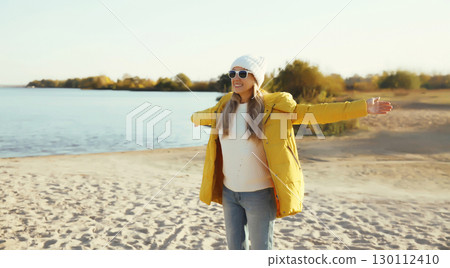 Happy smiling woman on beach, enjoying amazing landscape, warm weather standing on sea coast Happy smiling woman on beach, enjoying amazing landscape, warm weather standing on sea coast 130112410