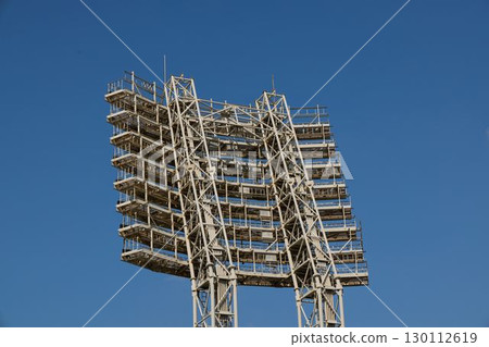 A sports stadiums floodlight structure prominently stands out against a clear blue sky 130112619