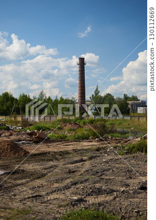 An Abandoned Industrial Site featuring a Smoke Stack prominently against a Blue Sky backdrop 130112669