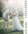 Fantasy landscape of a woman in a white dress touching a unicorn 130112829