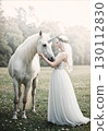 Fantasy landscape of a woman in a white dress touching a unicorn 130112830