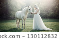 Fantasy landscape of a woman in a white dress touching a unicorn 130112832