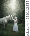 Fantasy landscape of a woman in a white dress touching a unicorn in the forest 130112835