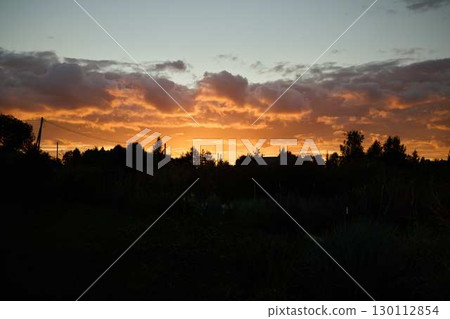 A Beautiful Sunset is Over the Hills with Vibrant Colors and Fluffy Clouds in the Sky 130112854