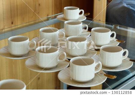 An Elegant Arrangement of White Coffee Cups Beautifully Displayed on Matching Saucers An Elegant Arrangement of White Coffee Cups Beautifully Displayed on Matching Saucers 130112858
