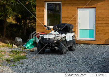 A vibrant outdoor ATV rests near a cozy, charming cabin surrounded by natures beauty A vibrant outdoor ATV rests near a cozy, charming cabin surrounded by natures beauty 130112963