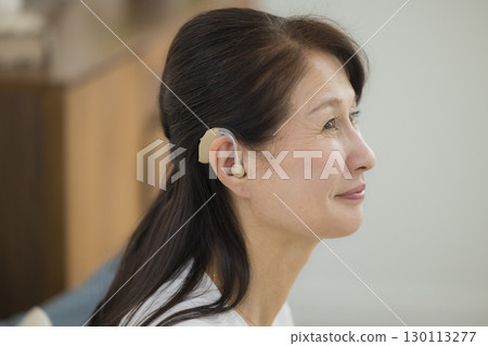 Senior woman wearing a hearing aid 130113277