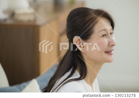 Senior woman wearing a hearing aid 130113278