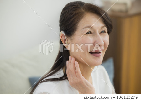 Senior woman wearing a hearing aid 130113279