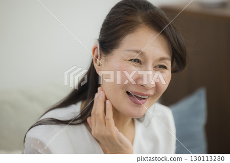 Senior woman wearing a hearing aid Senior woman wearing a hearing aid 130113280