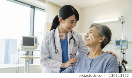 Female doctor assisting an elderly patient in a wheelchair 130113352