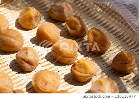 Close-up of plums being dried in the sun on a bamboo basket (pickled plums, doyo-boshi) 130113477