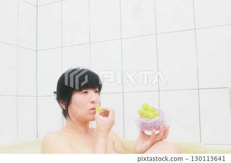 A young woman eating Shine Muscat grapes while taking a bath 130113641