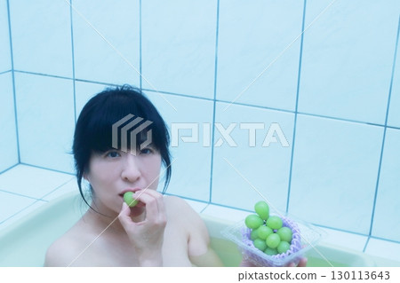A young woman eating Shine Muscat grapes while taking a bath 130113643