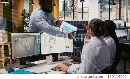 RD department colleagues brainstorming ways to make solar panels production lines more eco friendly. Teamworking technicians run simulation to optimize solar cells green energy levels, camera A 130114021