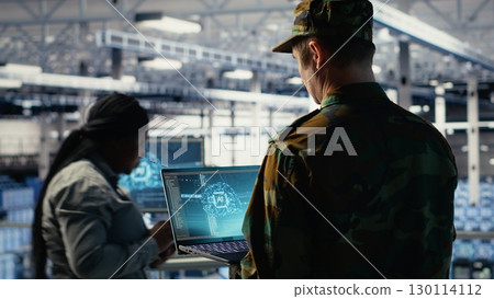 Soldier in engineering role uses AI application on laptop to manage server hub systems. Army commander reviews secret intelligence information using artificial intelligence in data center, camera B 130114112