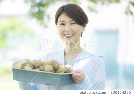 拿著收穫的馬鈴薯的女人 130114230