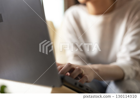 Selective focus on fingers of female remote worker typing on laptop keyboard. Closeup of woman entrepreneur working remotely on digital device, updating business reports on company progress. Selective focus on fingers of female remote worker typing on laptop keyboard. Closeup of woman entrepreneur working remotely on digital device, updating business reports on company progress. 130114310