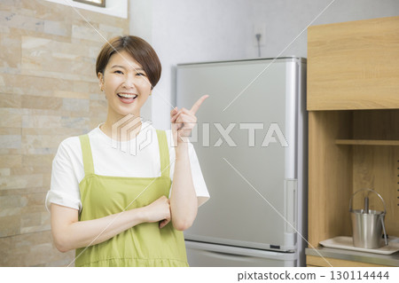 一名繫著圍裙的女子打開冰箱 130114444