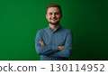 An approachable individual with a warm smile showcasing a casual outfit against a green setting 130114952