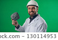 A smiling geologist pointing to a volcanic rock in their hand 130114953