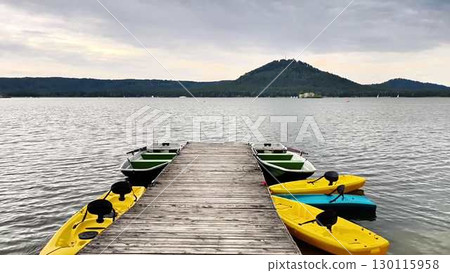 Lakeside Kayaking Dock featured with Vibrantly Colorful Kayaks set Beneath a Cloudy Sky Lakeside Kayaking Dock featured with Vibrantly Colorful Kayaks set Beneath a Cloudy Sky 130115958