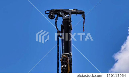 A Hydraulic Drill Rig Set Against a Clear Blue Sky Background, Showcasing Powerful Equipment 130115964