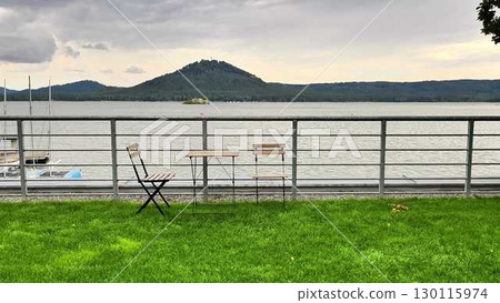 Experience a breathtaking scenic lakeside view complete with a table and chairs nestled in nature 130115974