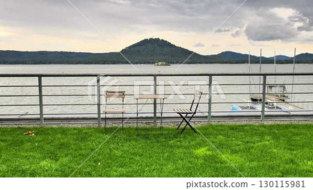 A Beautiful and Serene Lakeside View Featuring Tables and Chairs for Relaxation and Enjoyment A Beautiful and Serene Lakeside View Featuring Tables and Chairs for Relaxation and Enjoyment 130115981
