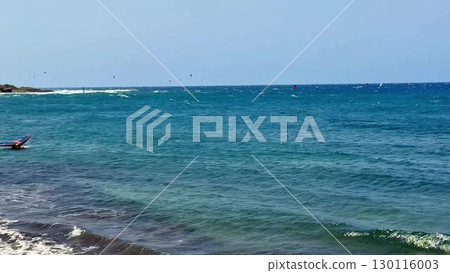 A scenic tropical seaside view featuring windsurfers skillfully navigating the waves 130116003