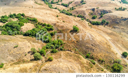 Dry grass on a rocky hill with a path leading toward a distant mountain in the rural Spanish countryside Dry grass on a rocky hill with a path leading toward a distant mountain in the rural Spanish countryside 130116299