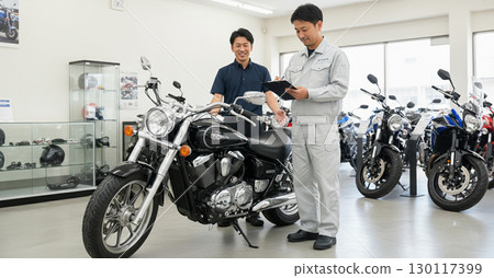 A customer and a salesperson negotiating at a motorcycle shop A customer and a salesperson negotiating at a motorcycle shop 130117399
