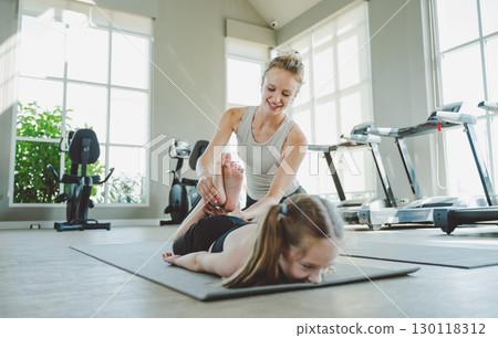 Mother Assisting Daughter in Deep Stretch Pose During Yoga 130118312