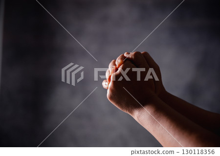 Christian woman lifts her hand in worship to pray, hope, faith, and deep belief in God defines core concept of religion. Praying hands with faith in religion, belief in God. Power of hope or love. 130118356