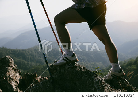 Hiking boot. Close up of female legs in boots on hiking trail on top of mountain outdoor. young woman reaching top of mountain. women feet wearing hiking boots on rock. Travel, vacation concept. 130119324