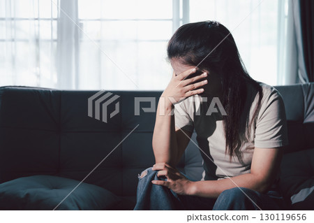 Despair sorrow person in empty dark room, Depressed young woman covering face with hands. Young woman coping with distress covering face. mental health concept. Boring sad upset frustrated stressed. 130119656