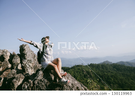 Woman hiker on top of mountain. Hiker with arms up on top of mountain successful young woman enjoying triumph. traveler exploring world. Hikers with backpacks relaxing. Sport and success concept. Woman hiker on top of mountain. Hiker with arms up on top of mountain successful young woman enjoying triumph. traveler exploring world. Hikers with backpacks relaxing. Sport and success concept. 130119963