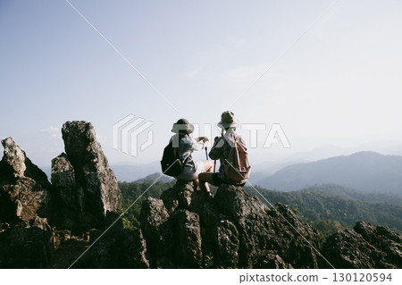 Woman hiker on top of mountain. Hiker with arms up on top of mountain successful young woman enjoying triumph. traveler exploring world. Hikers with backpacks relaxing. Sport and success concept. Woman hiker on top of mountain. Hiker with arms up on top of mountain successful young woman enjoying triumph. traveler exploring world. Hikers with backpacks relaxing. Sport and success concept. 130120594