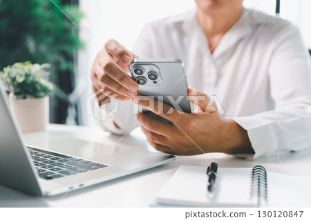 Close-up scene, a female seated at a table holds a smartphone, spending time on modern e-date services and social media through a mobile app, illustrating the wireless concept of digital usage. Close-up scene, a female seated at a table holds a smartphone, spending time on modern e-date services and social media through a mobile app, illustrating the wireless concept of digital usage. 130120847