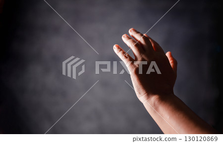 Christian woman lifts her hand in worship to pray, hope, faith, and deep belief in God defines core concept of religion. Praying hands with faith in religion, belief in God. Power of hope or love. 130120869