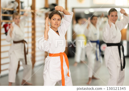 Young woman practicing kata standing in row with others 130121345